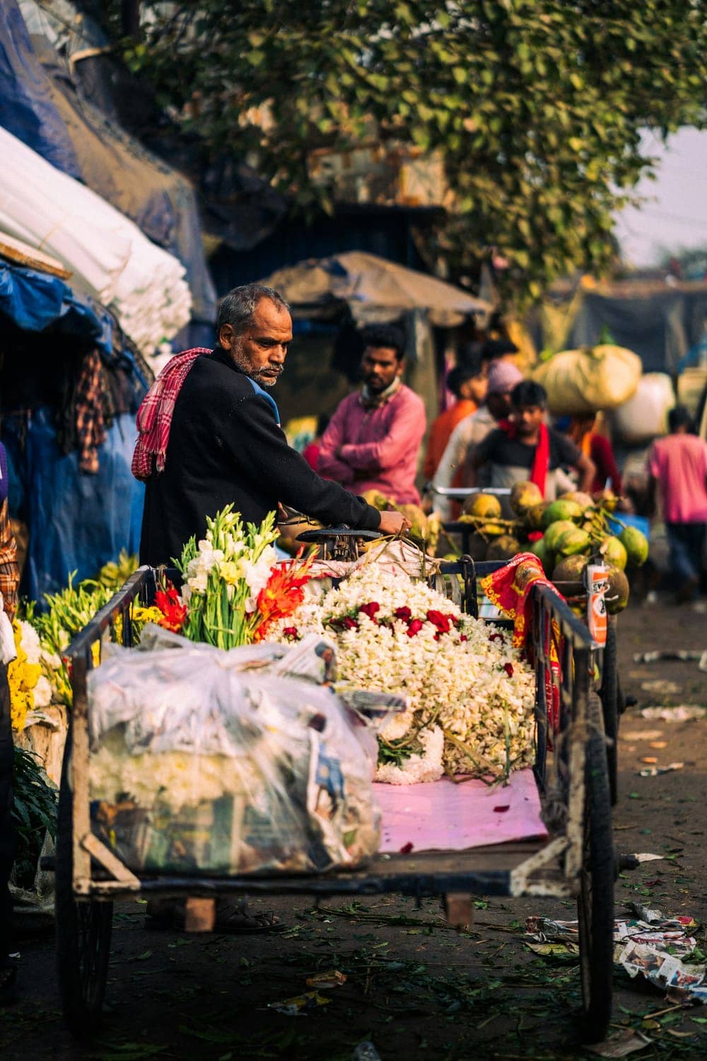 A flower vendor with a cart stacked with marigolds