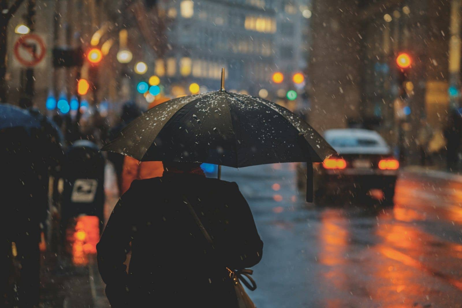 A person with an umbrella in the rain at night